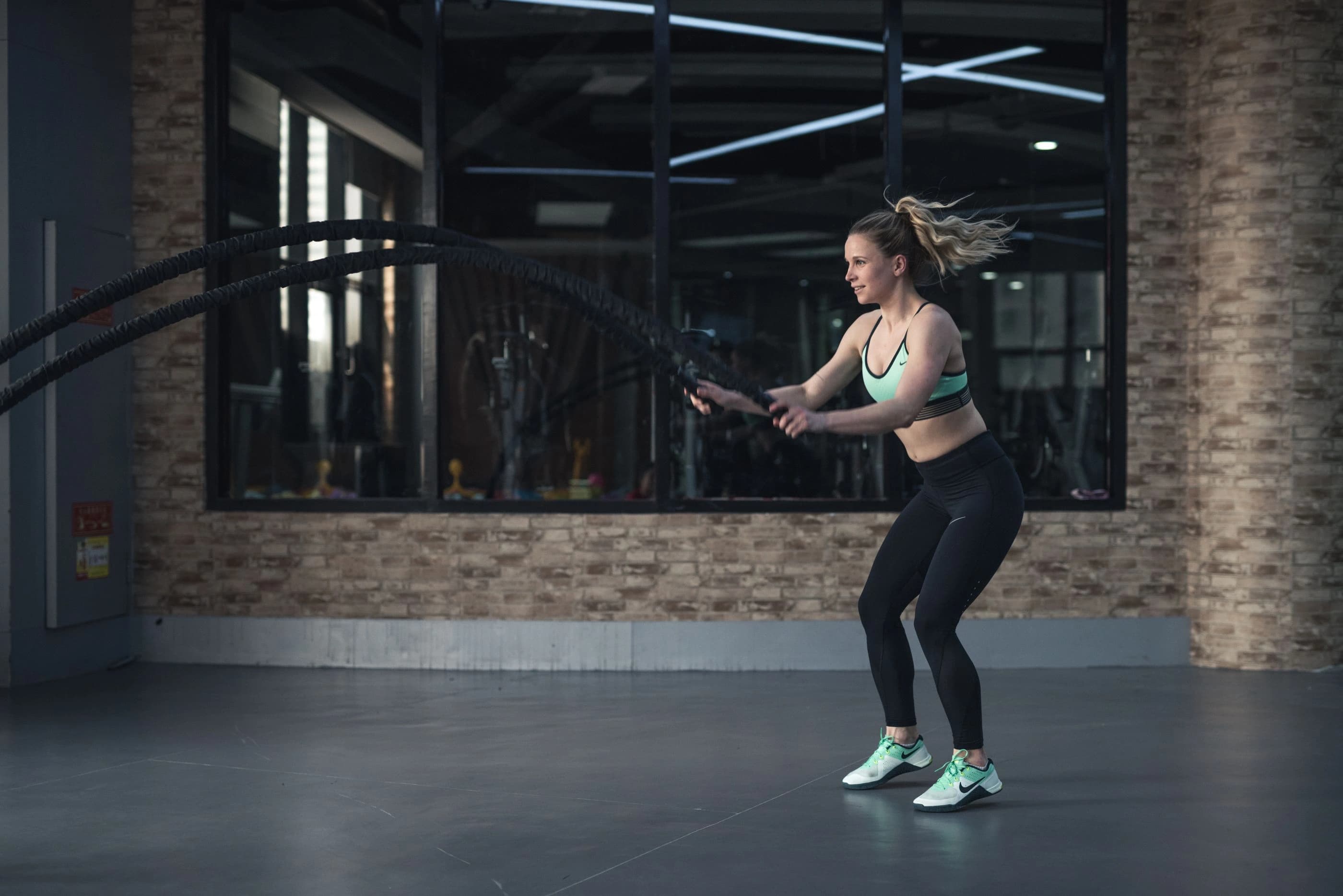 A woman training with battle ropes in a modern gym